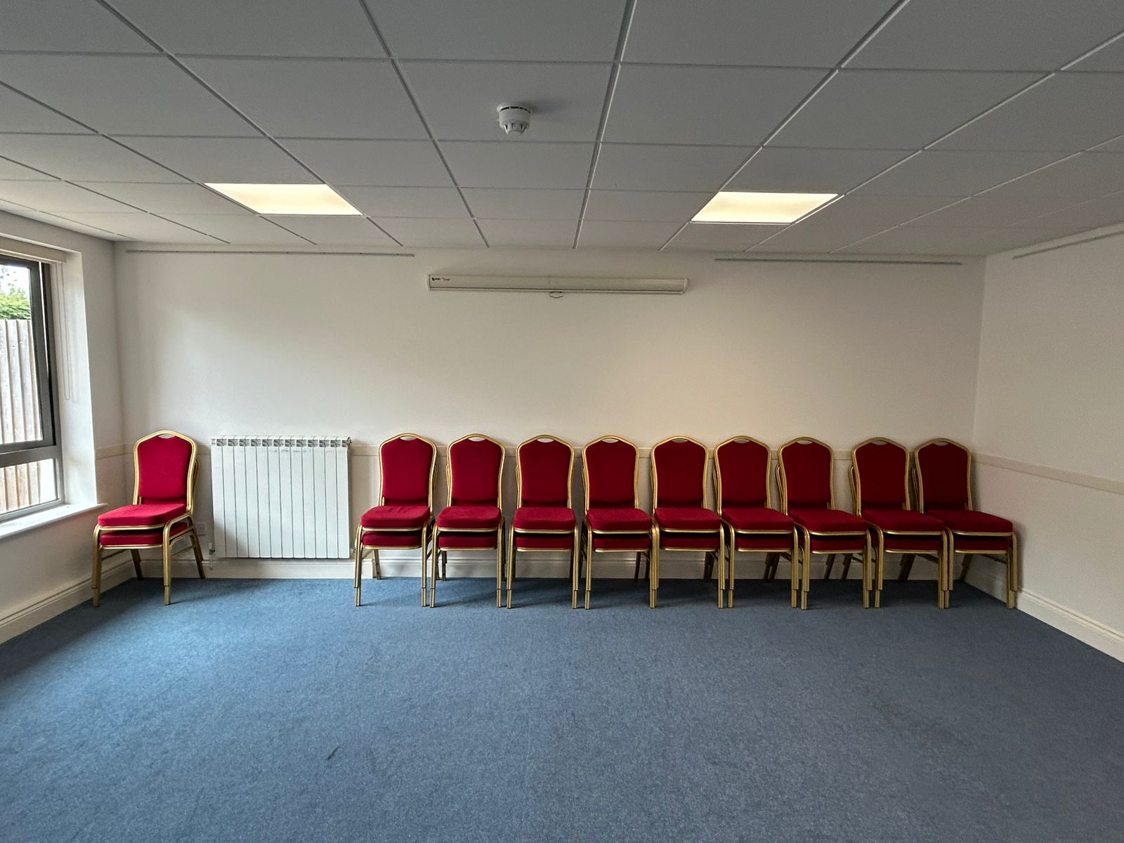 Commercial hall in Guernsey with freshly painted white walls and stacking chairs