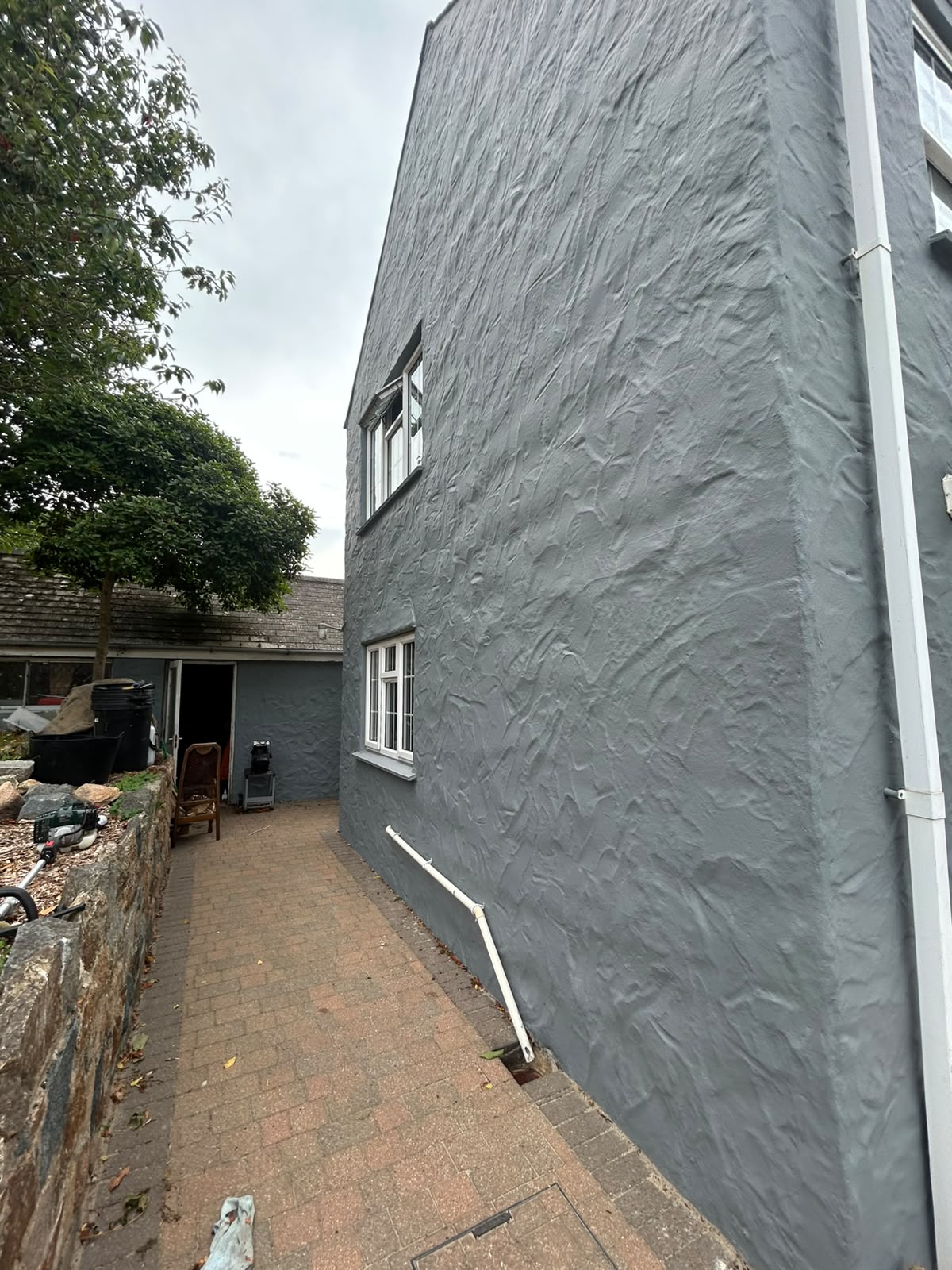 Side elevation showing textured render freshly repainted alongside original stonework