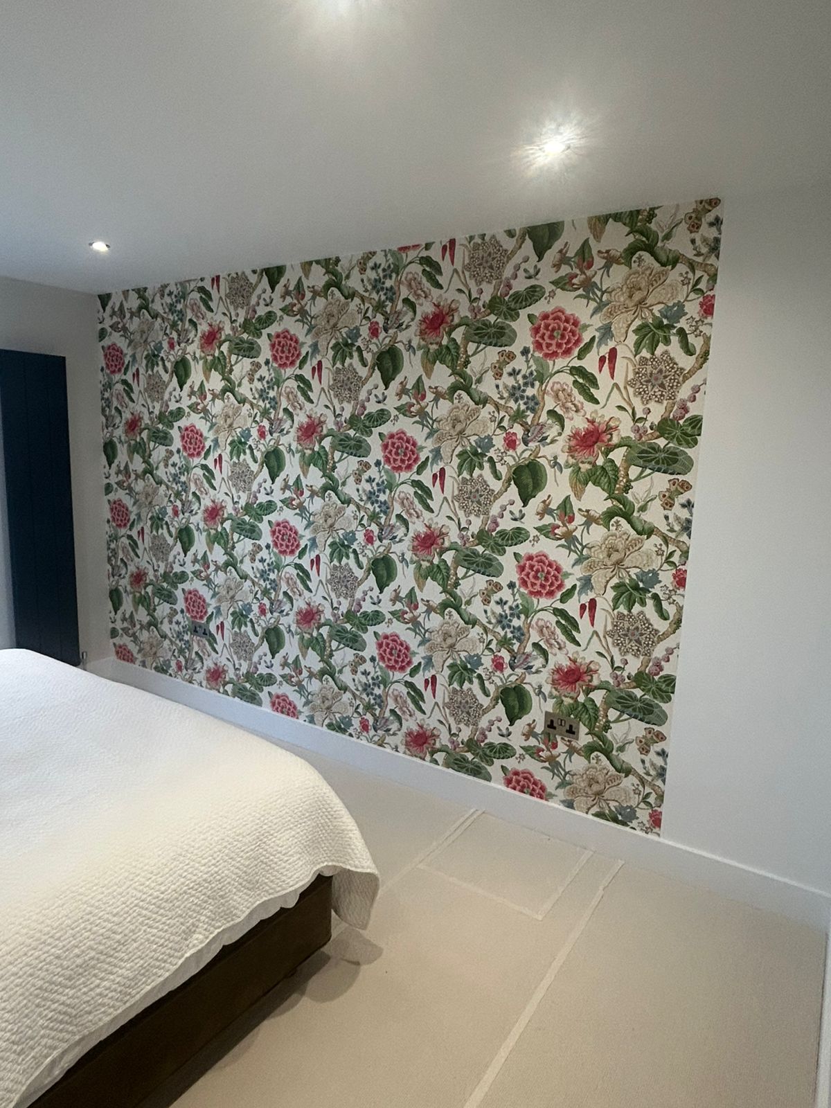 Wallpapered feature wall alongside freshly painted white walls and ceiling in a Guernsey bedroom