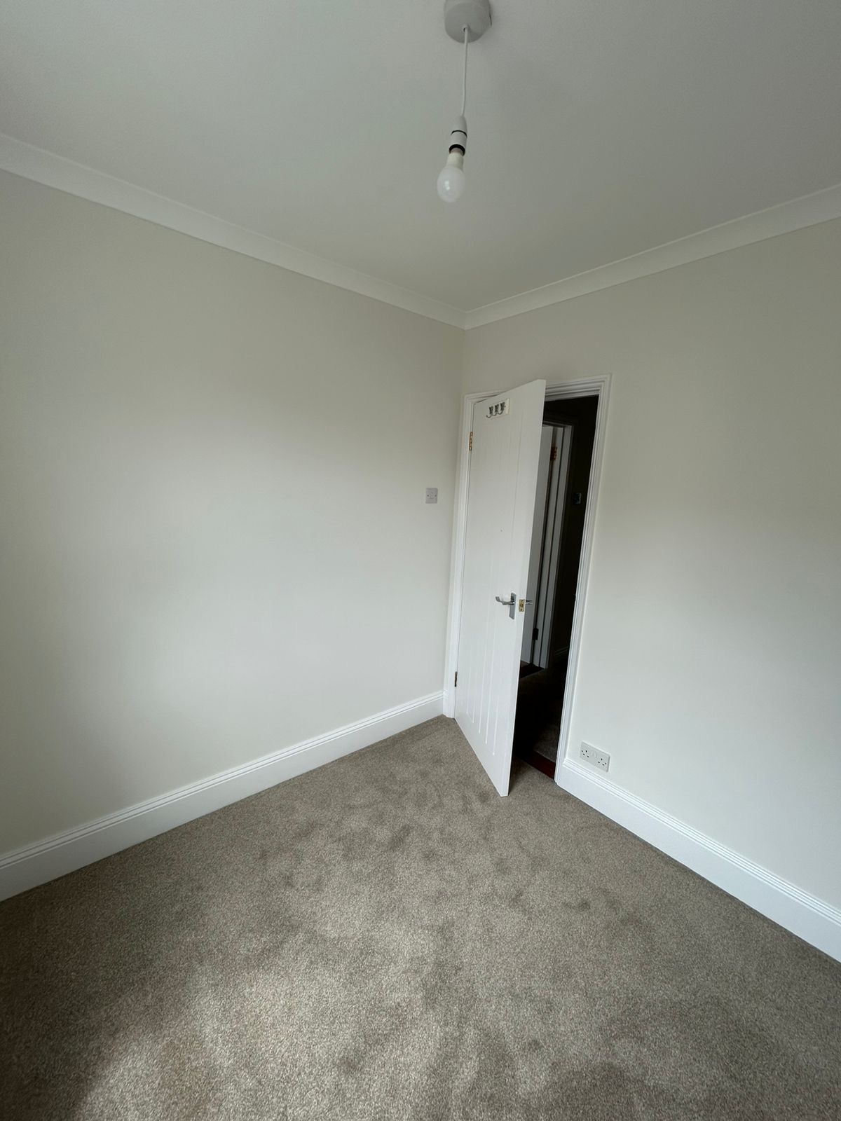 Small bedroom with clean neutral walls and painted door