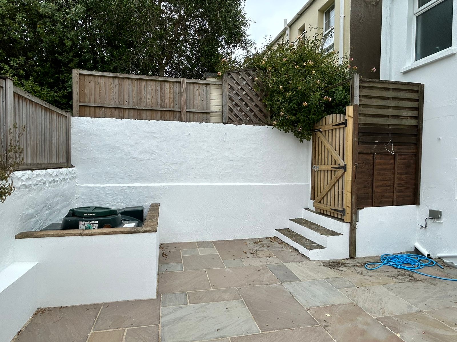 Courtyard boundary wall repainted in white with slate patio