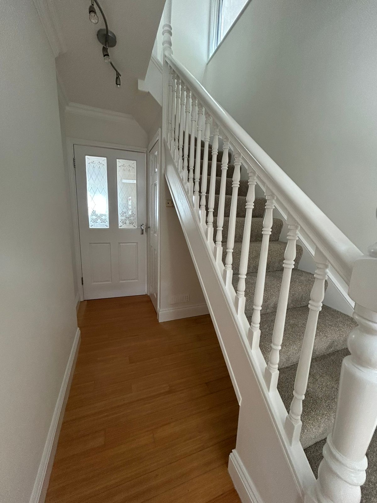 Entrance hallway with freshly painted white banister and stained-glass front door