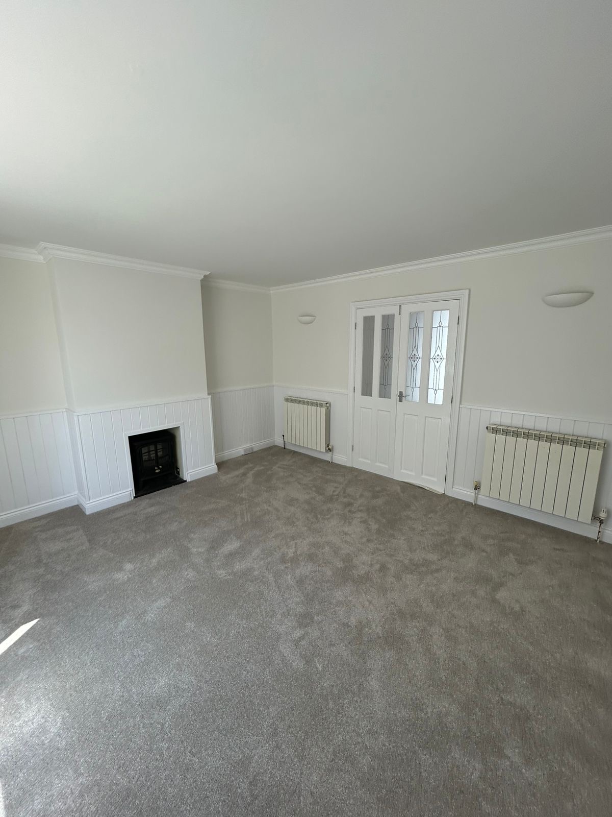 Living room with wainscot panelling, fireplace and glazed doors freshly painted