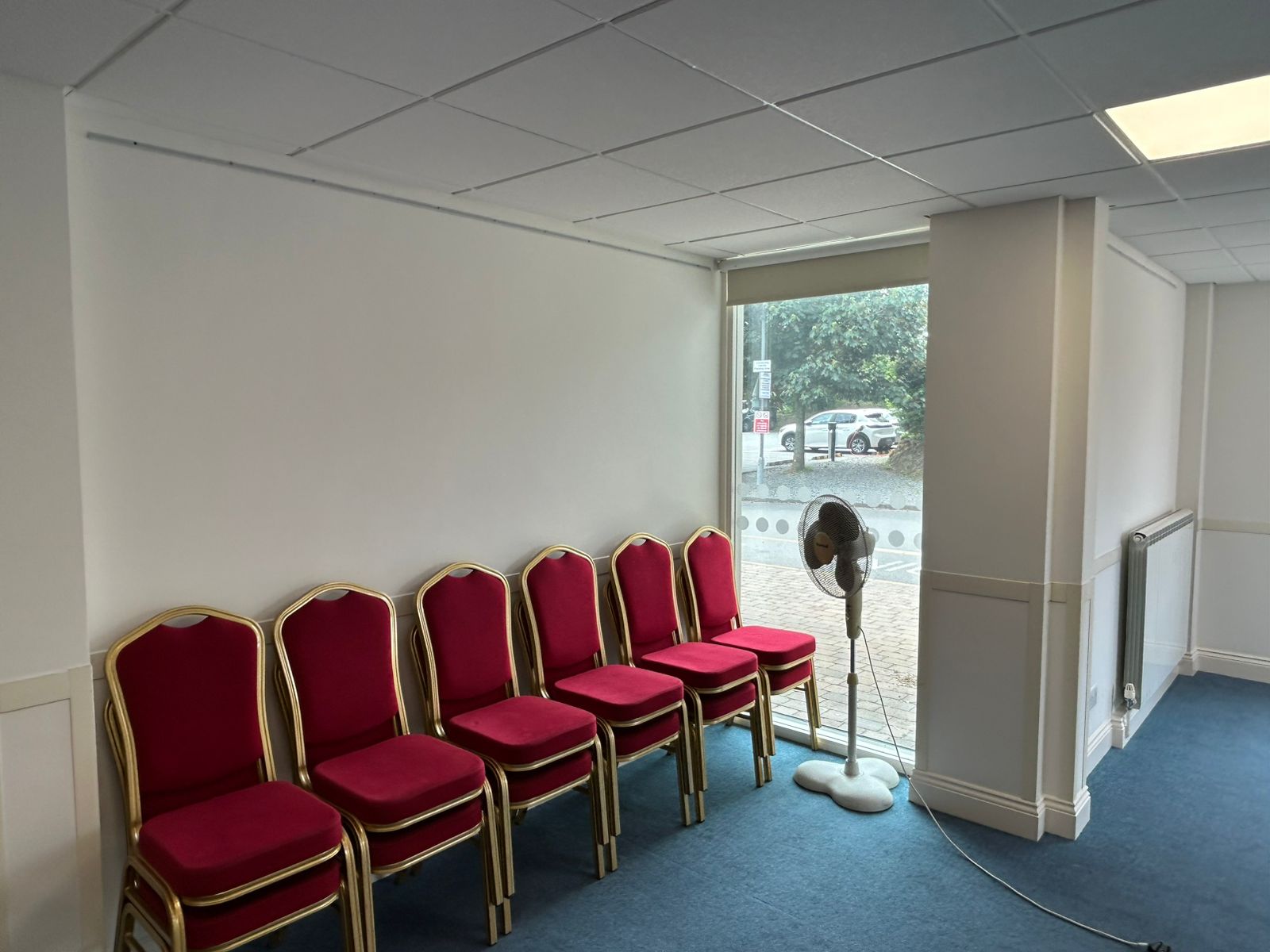 Community room with red chairs, painted trim and window to street