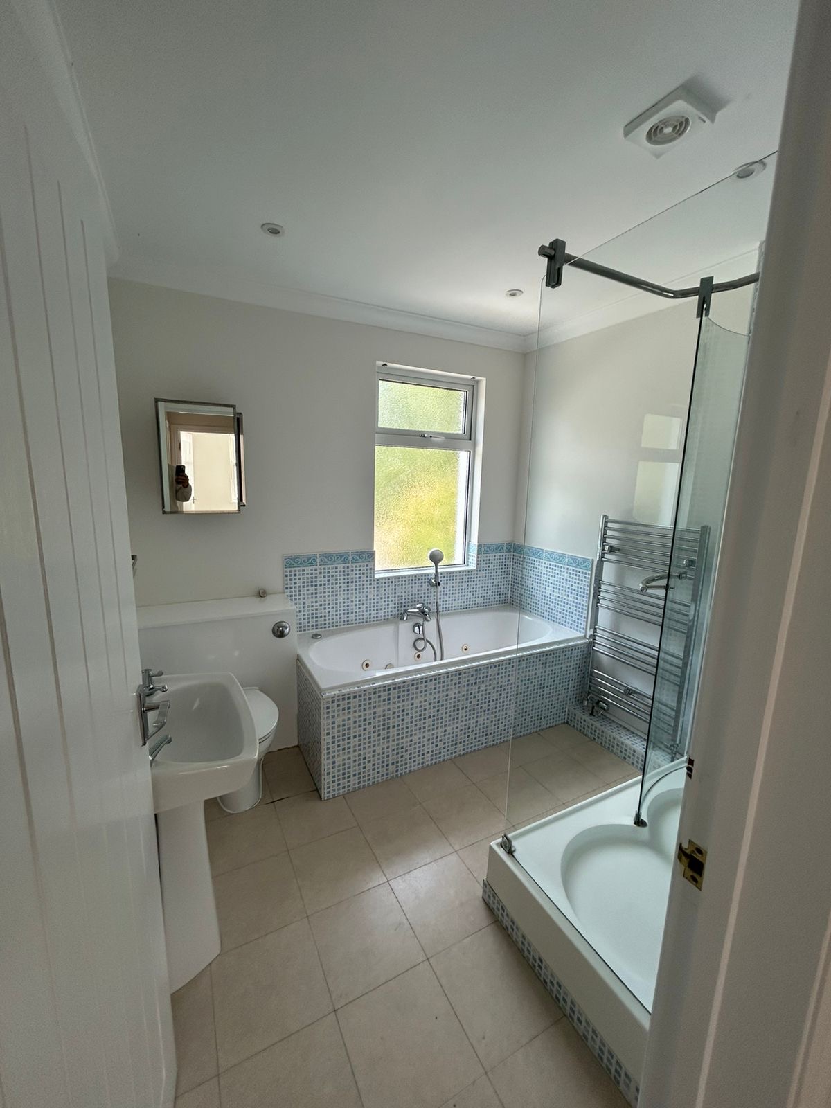 Family bathroom with freshly painted white walls and ceiling around mosaic tiling