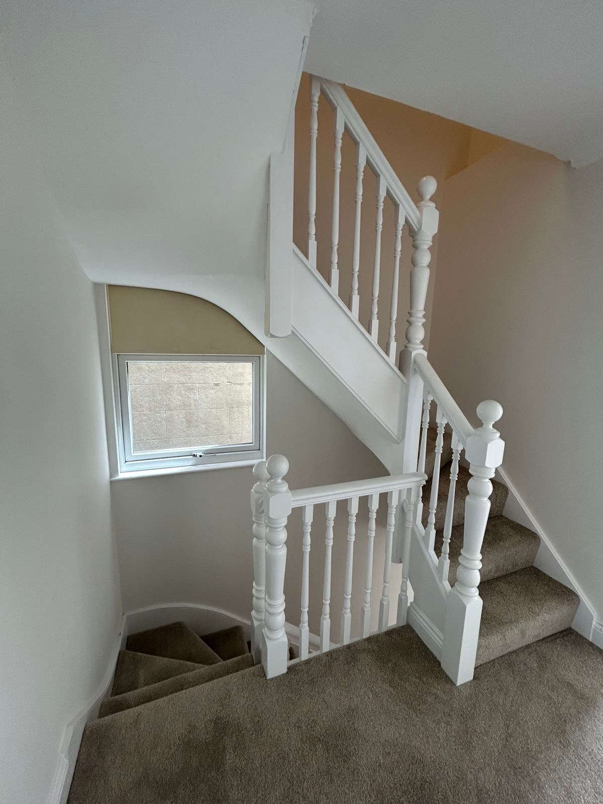 Staircase with white banister, spindles and neutral painted walls