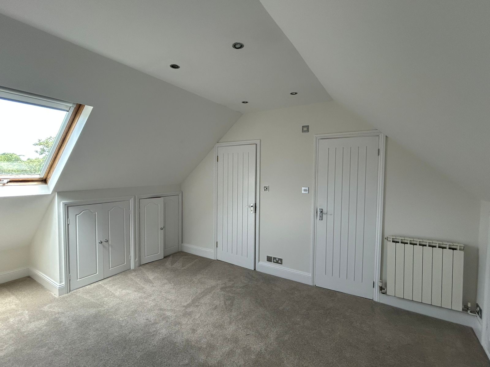 Loft bedroom with sloped ceiling, skylight and freshly painted doors