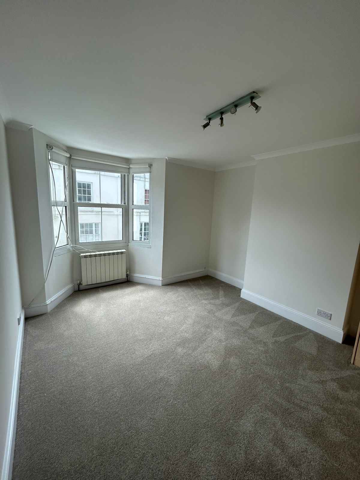 Town apartment living room with bay sash window, freshly painted walls and white trim