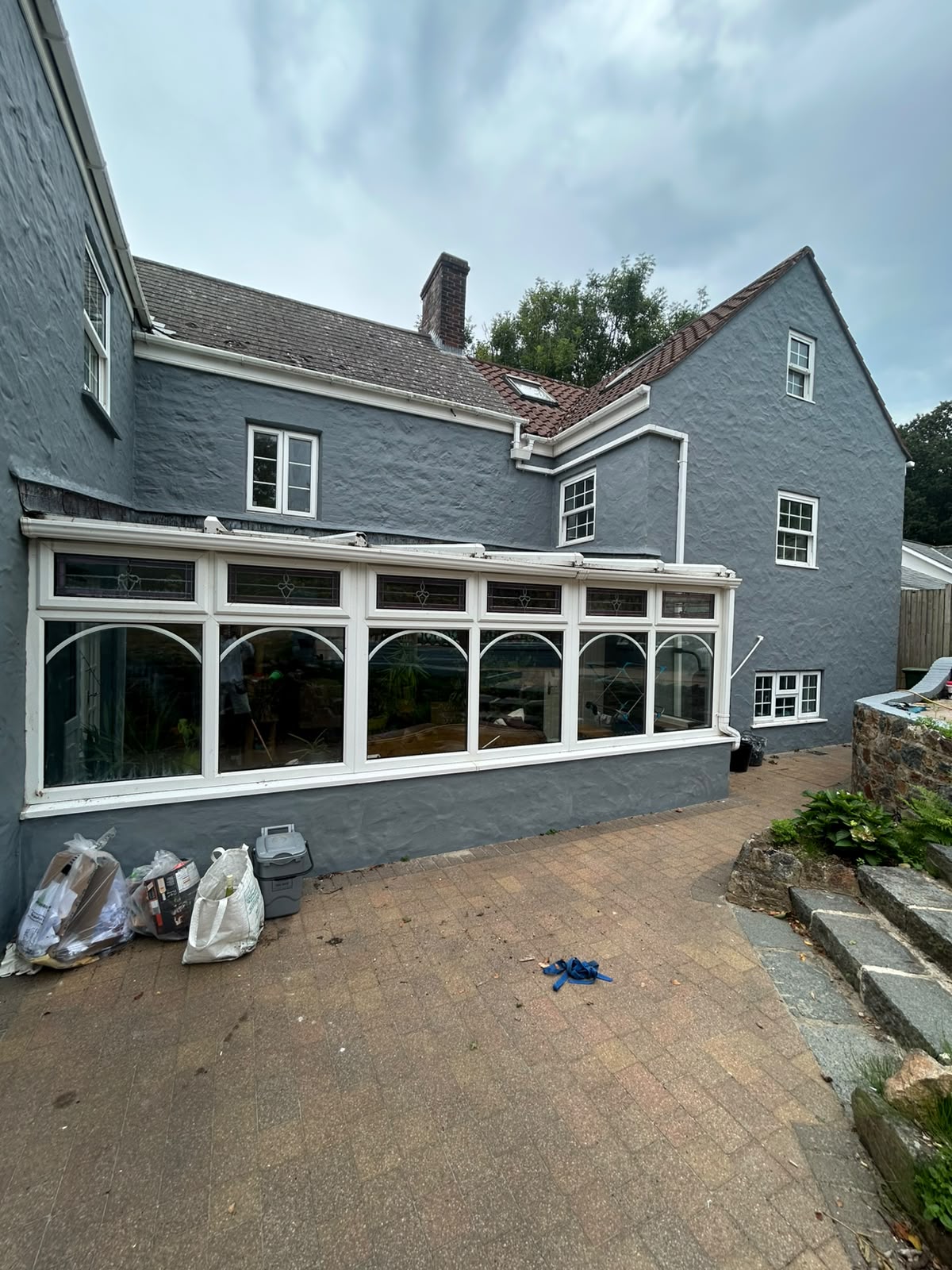 Rear elevation of the property freshly painted in slate grey with white conservatory frames