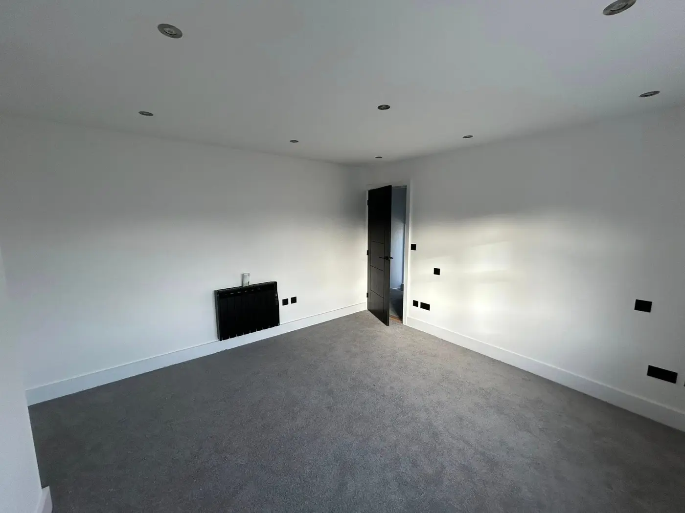 Upper bedroom with black door, radiator and spotlights