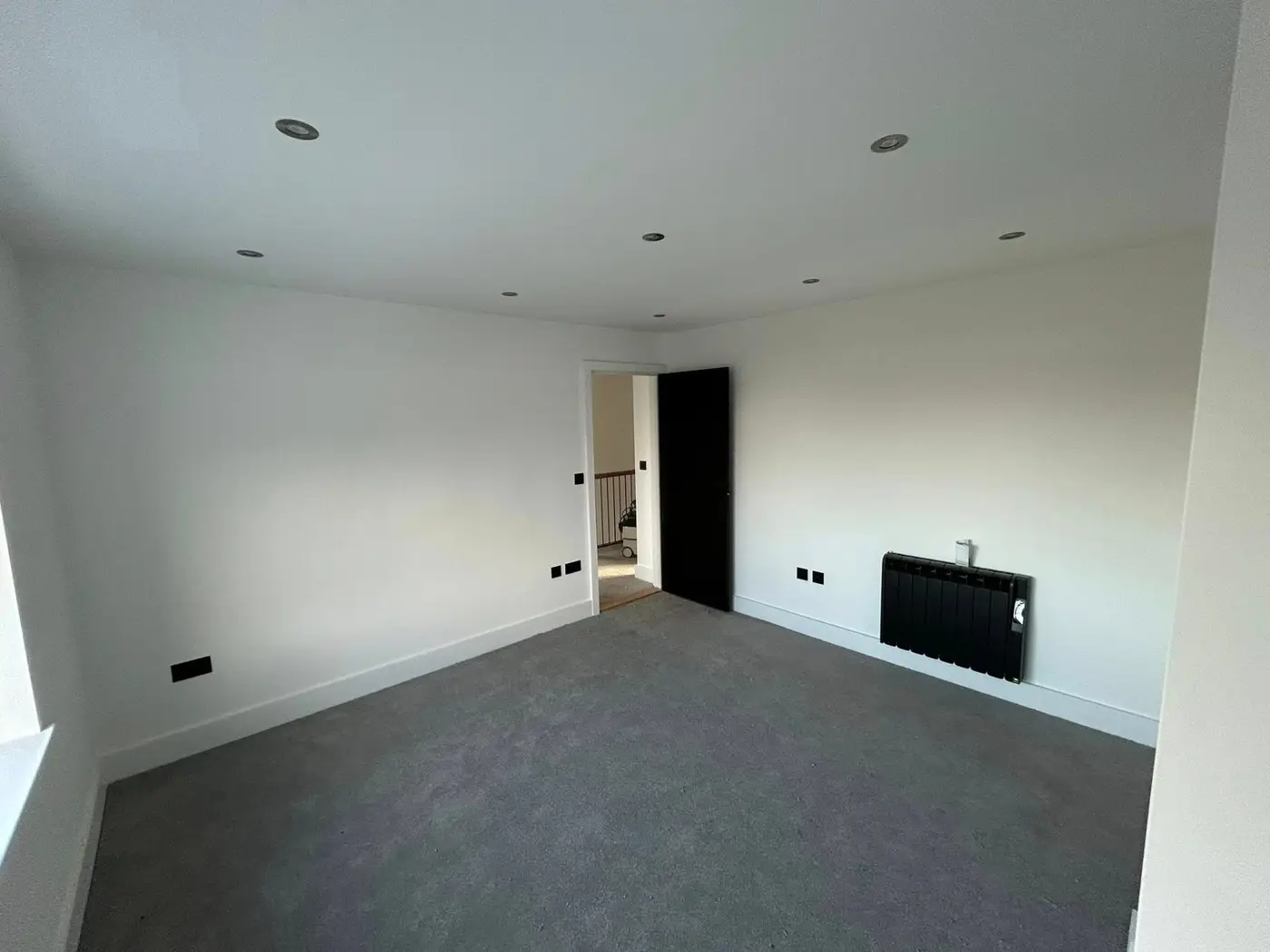 Spacious bedroom with black radiator and carpet throughout