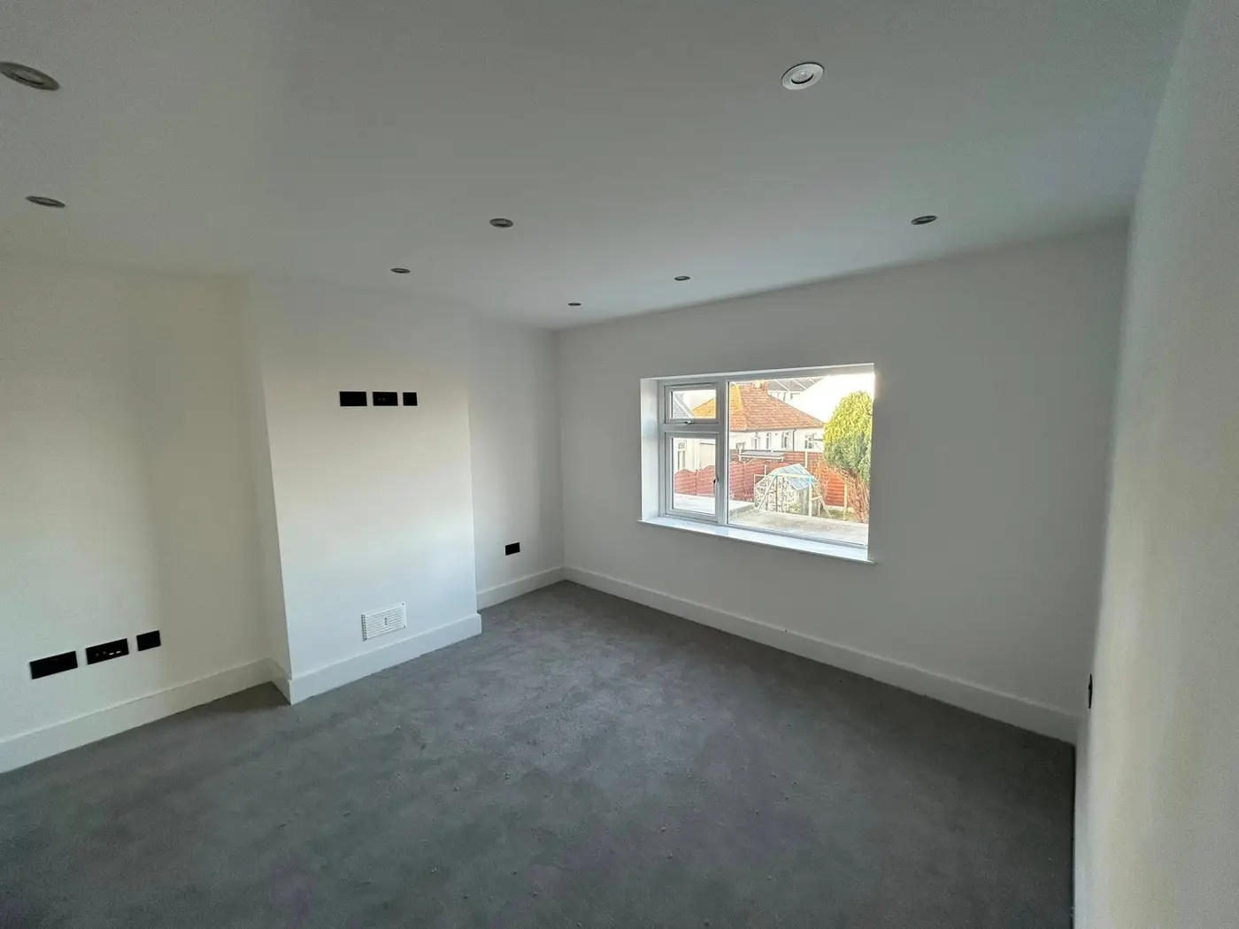 Large bedroom with window view, white walls and grey carpet