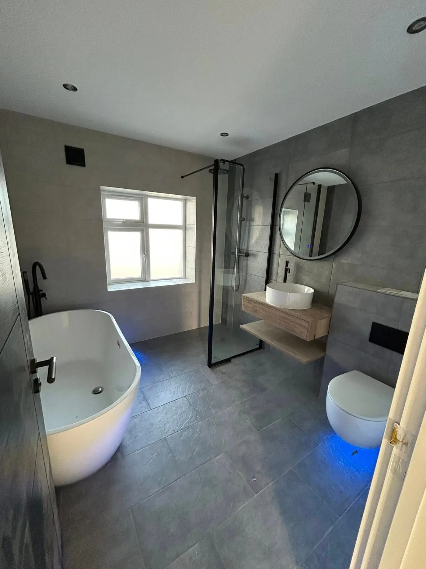 Luxury bathroom with freestanding bath, walk-in shower and blue LED lighting