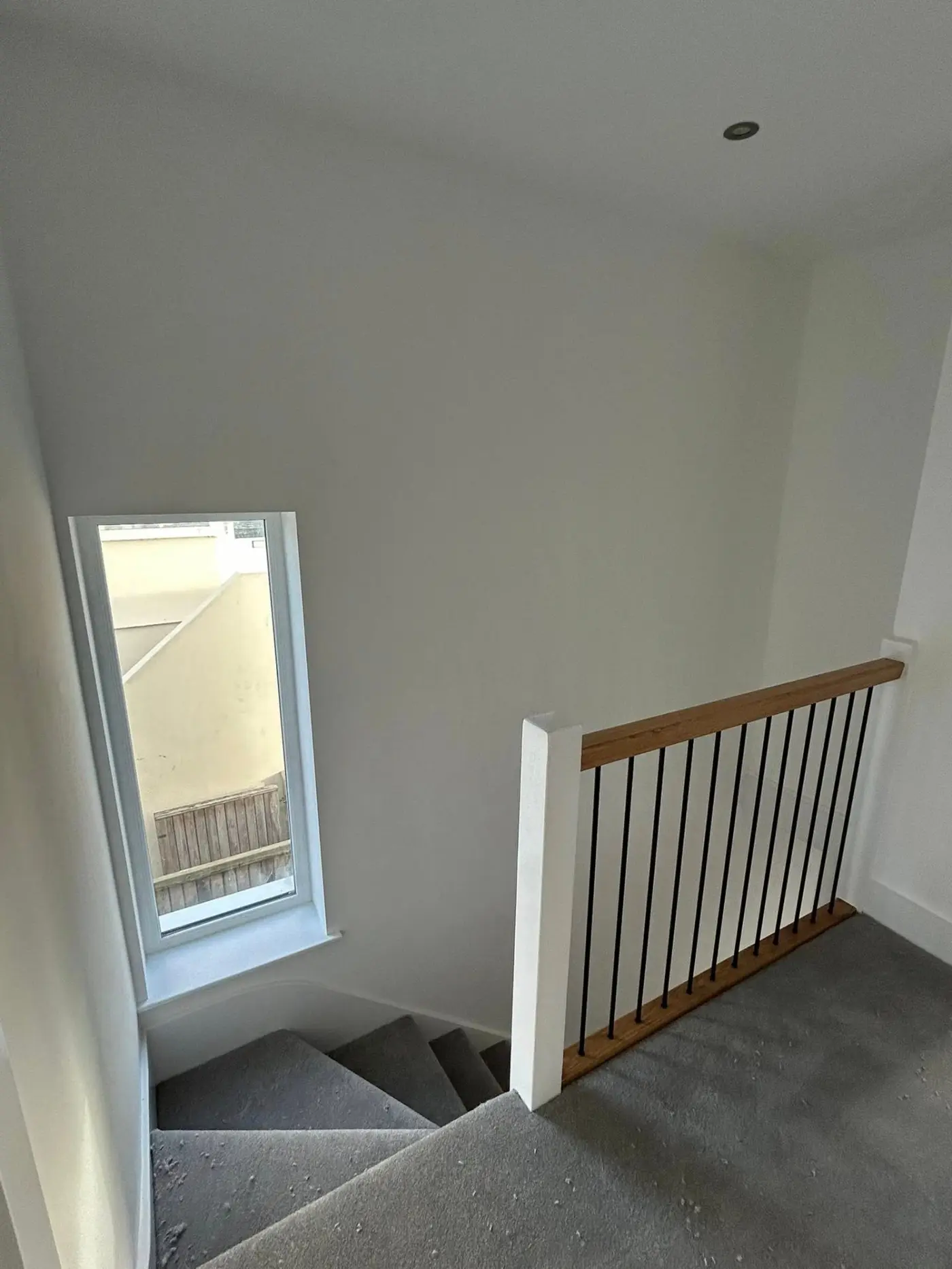 Staircase landing with oak and metal balustrade, freshly painted walls