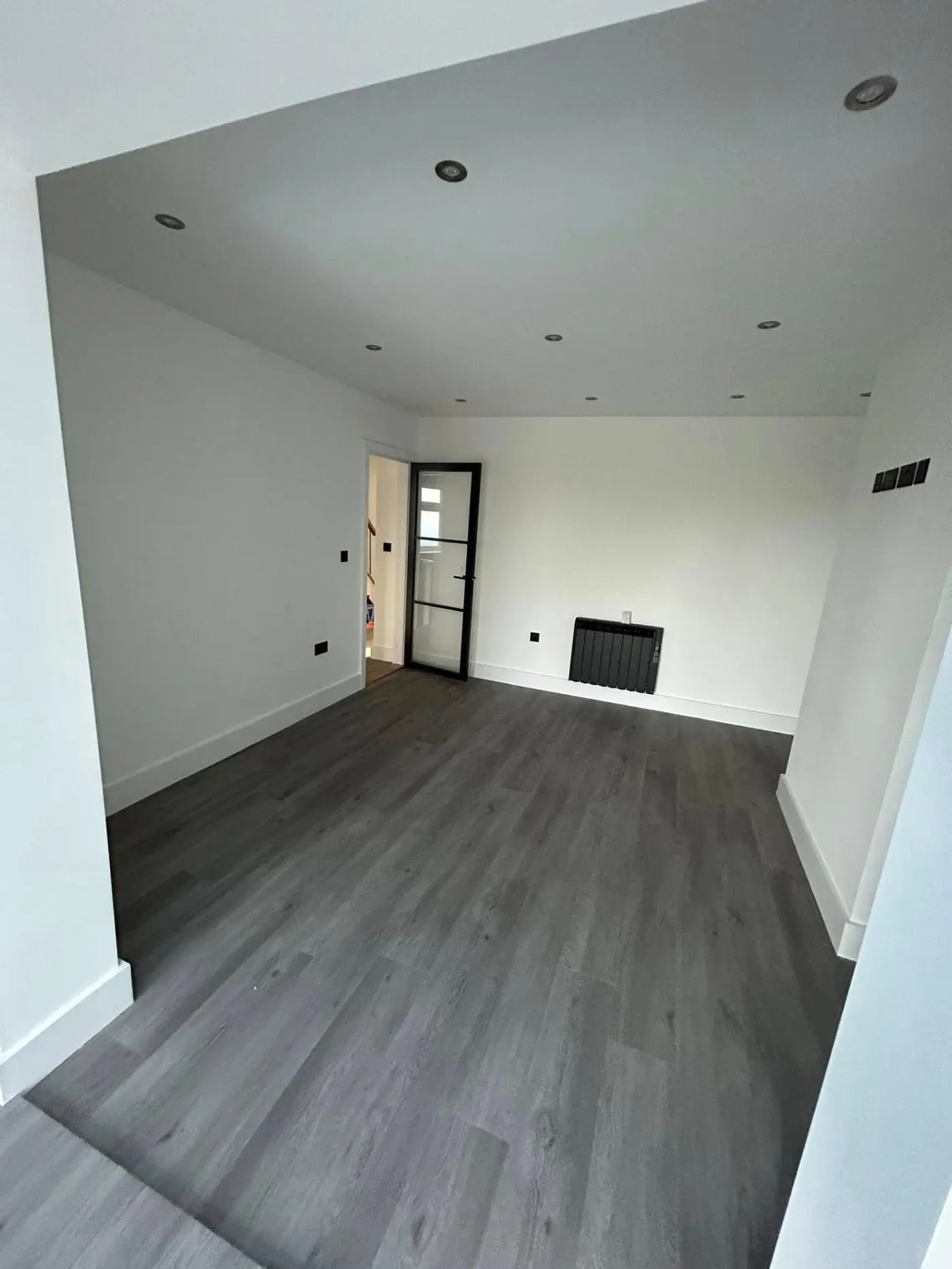 Living room with grey flooring, white walls and glass door