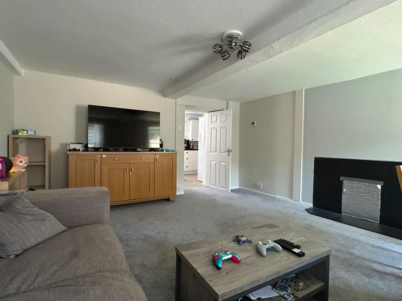 Lounge with warm neutral walls, wooden media console, feature beam and fireplace