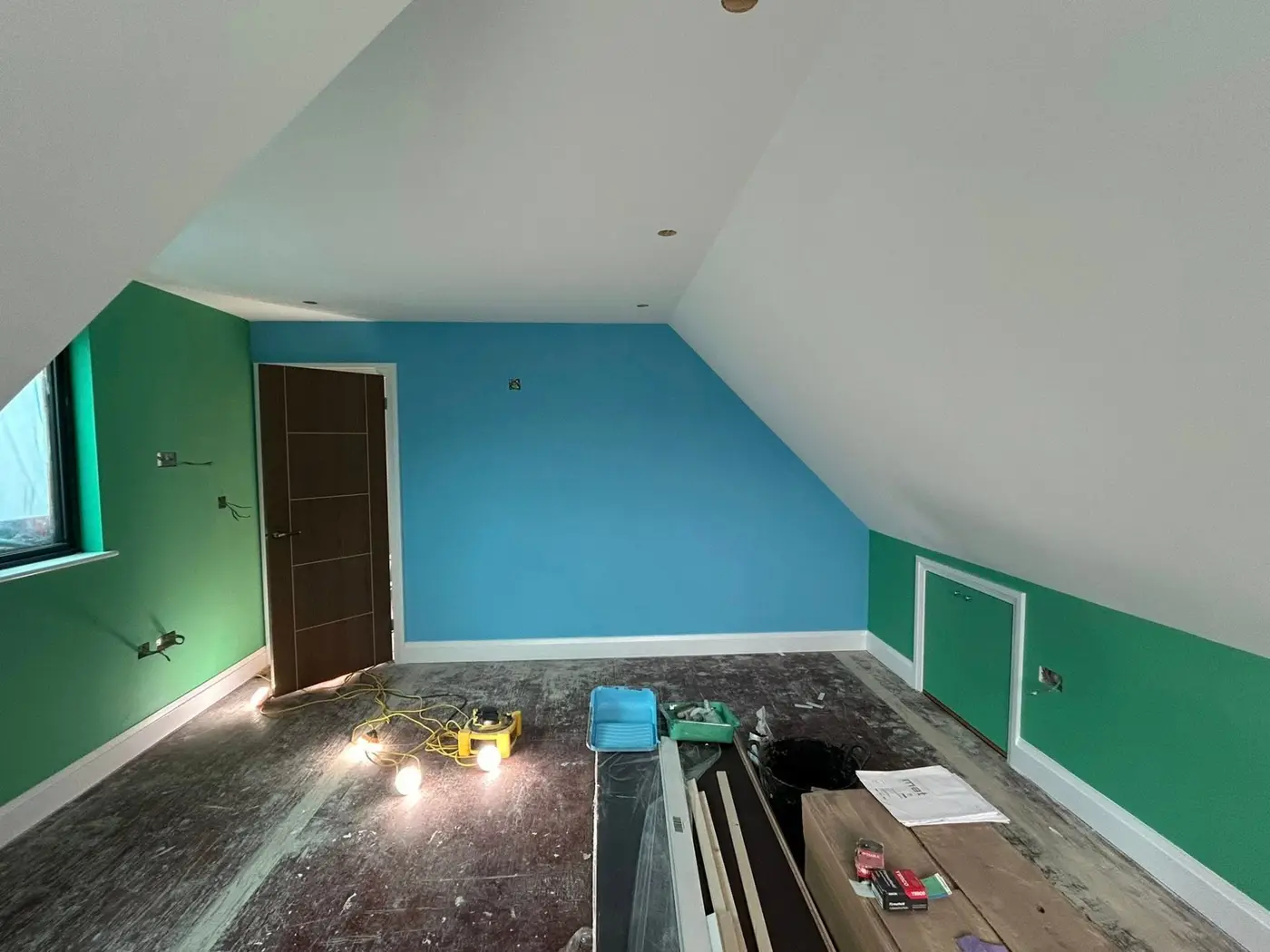 Loft room with blue and green feature walls and dark wood door