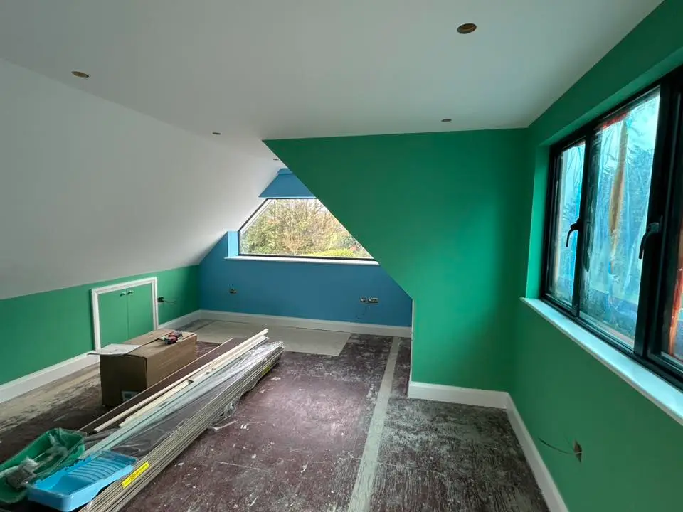 Loft room with green walls and natural light through windows