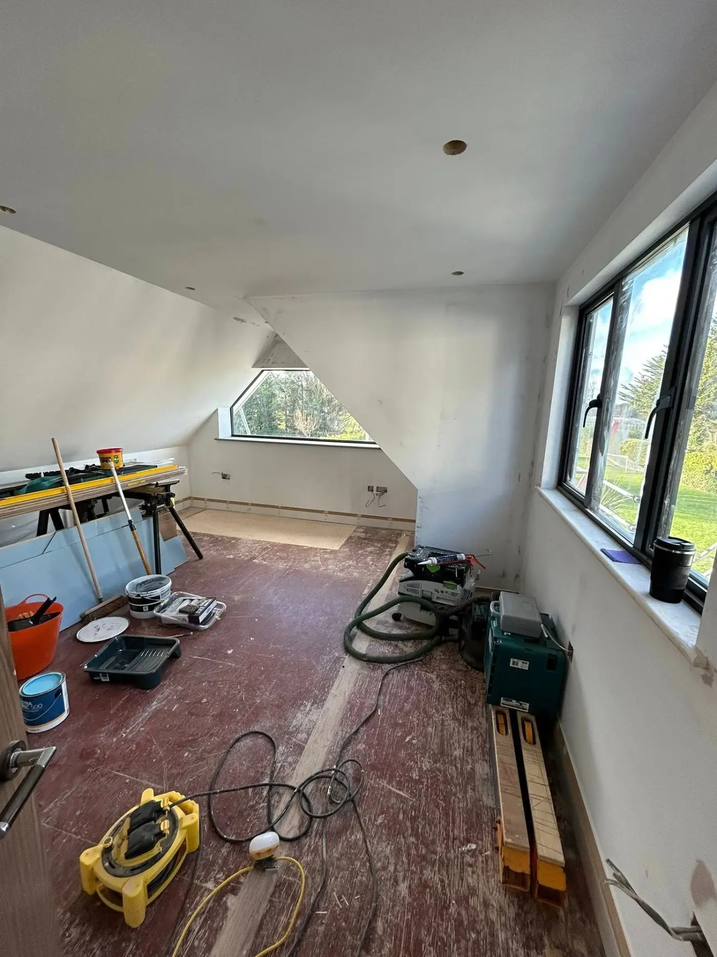 Loft room before — unpainted walls with equipment on floor