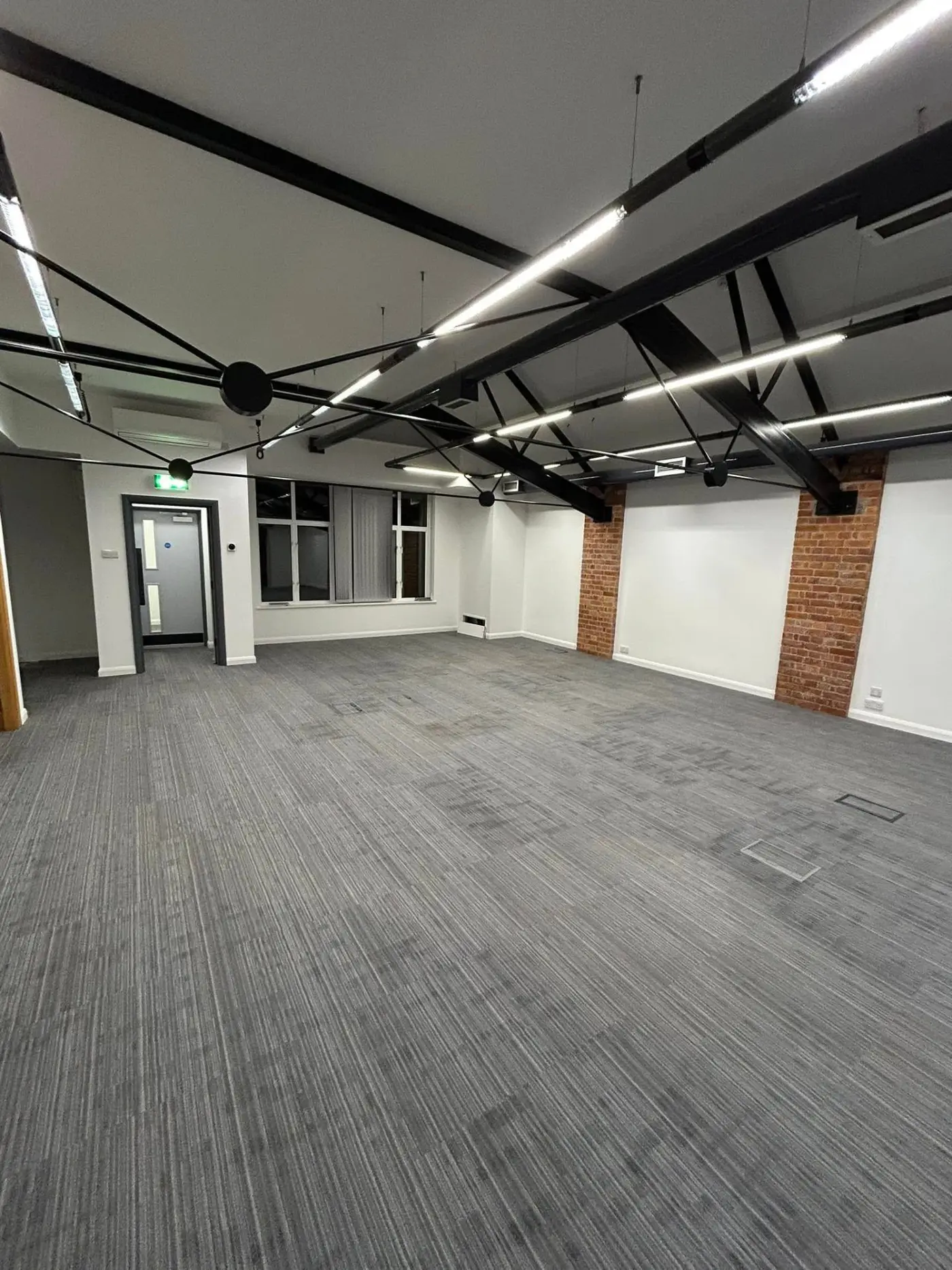 Large open-plan office with exposed beams and brick walls
