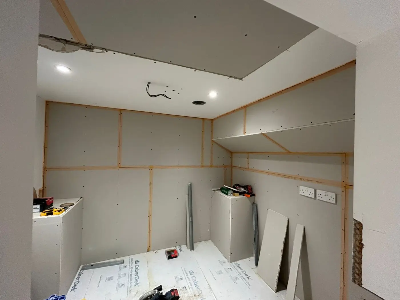 Room before — exposed timber battens and plasterboard