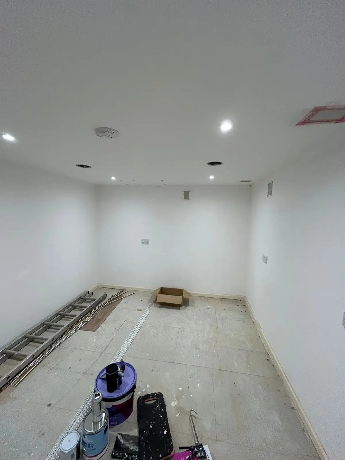 Room before — freshly plastered walls with paint supplies